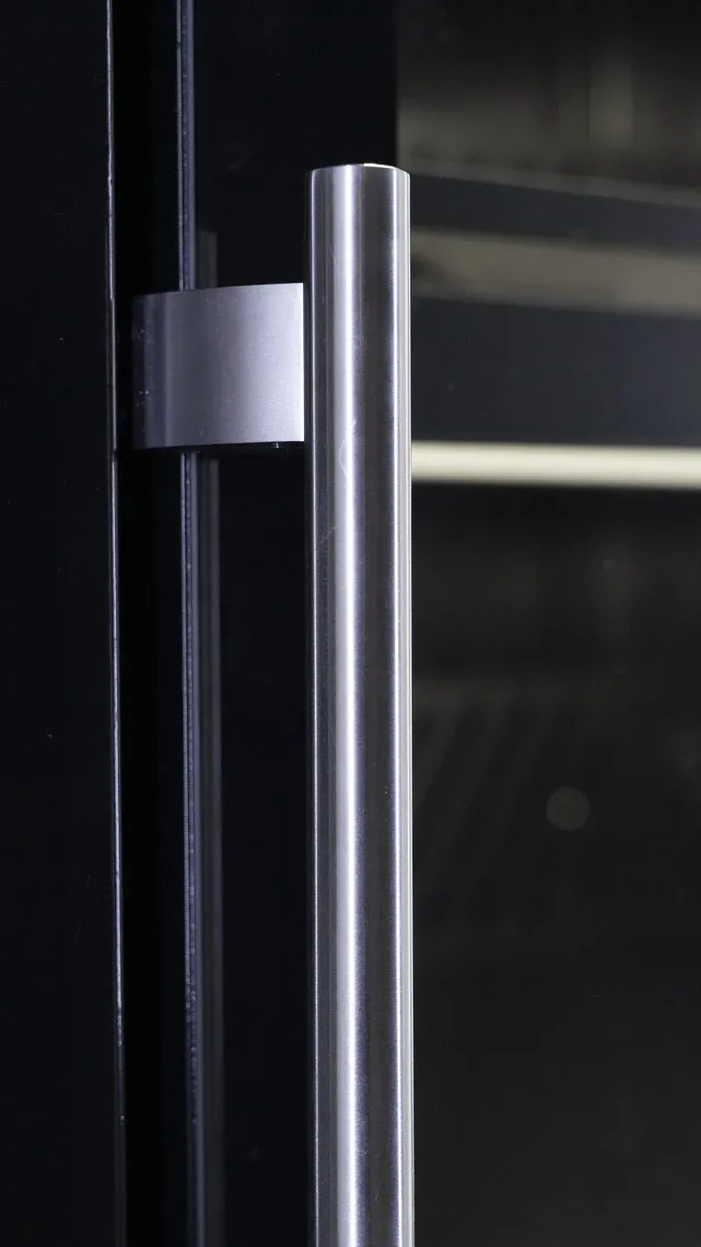 Vertical metal handle on the glass door of a cabinet