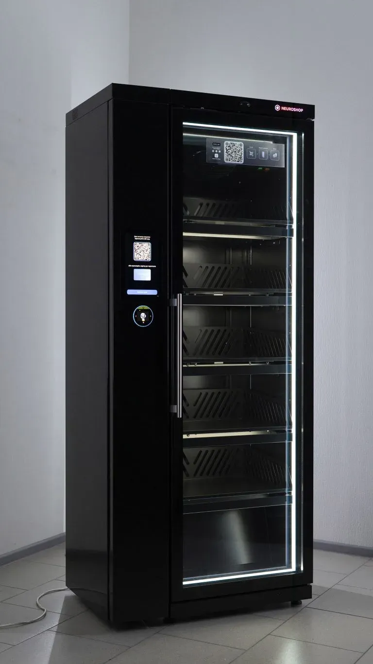 Black cabinet with a glass door, empty lit shelves inside, a screen with a QR code on the front panel