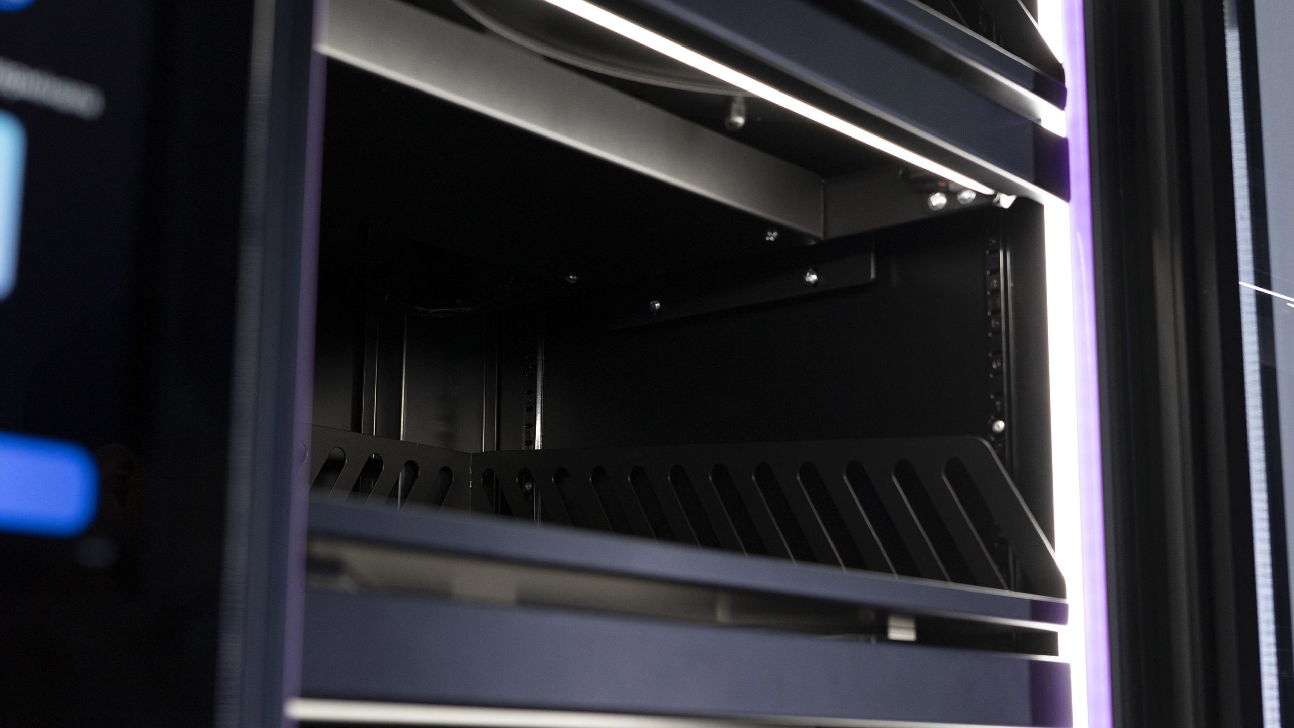 Empty shelf with a slotted front edge inside a cabinet, LED lighting above